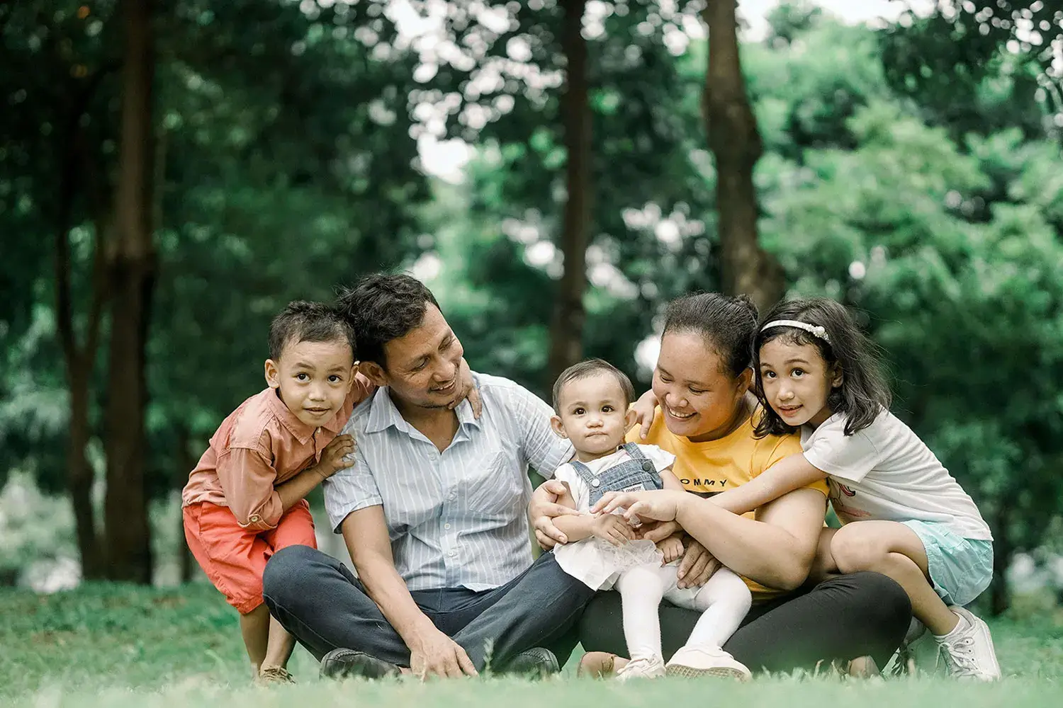Exterminator maintenance program: A family sitting on the ground in front of trees.