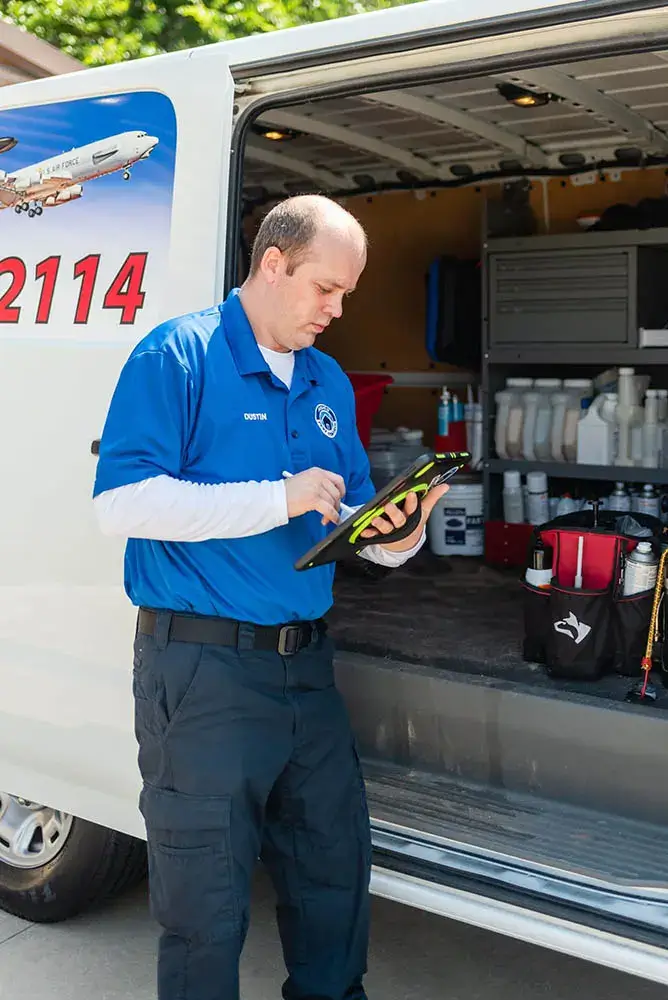 A man in blue shirt holding a tablet near a truck.